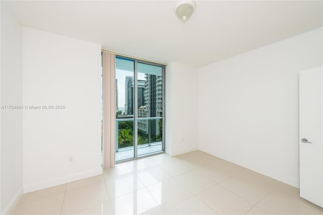 spare room featuring floor to ceiling windows and light tile patterned flooring