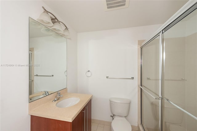 bathroom with tile patterned floors, vanity, toilet, and a shower with door