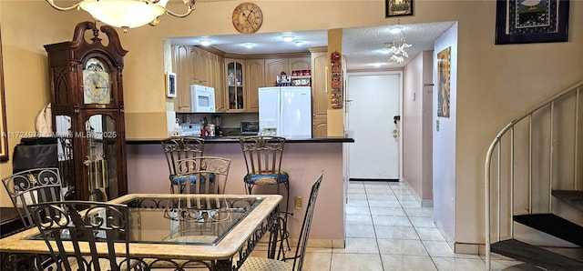 kitchen with white appliances, kitchen peninsula, a textured ceiling, and light tile patterned floors