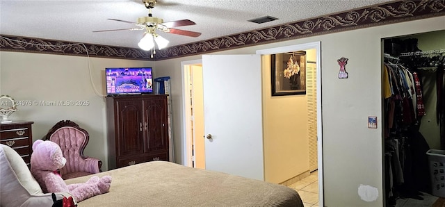 bedroom with a textured ceiling, ceiling fan, light tile patterned floors, and a closet