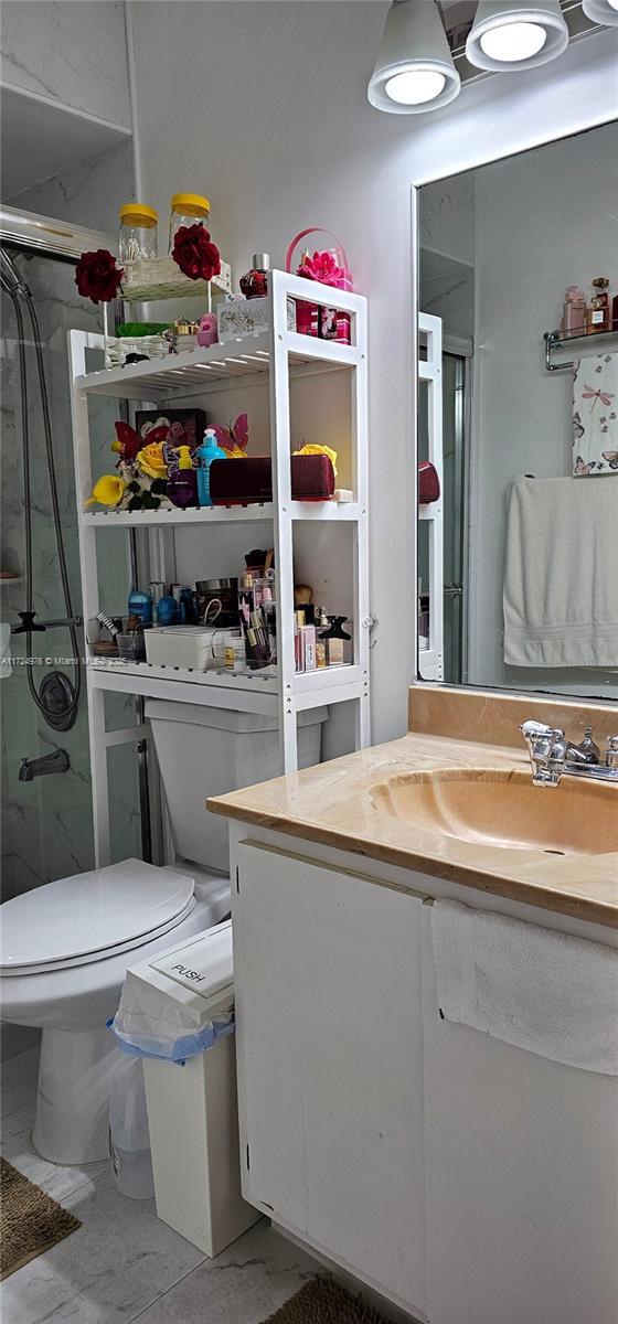 bathroom with walk in shower, vanity, and toilet