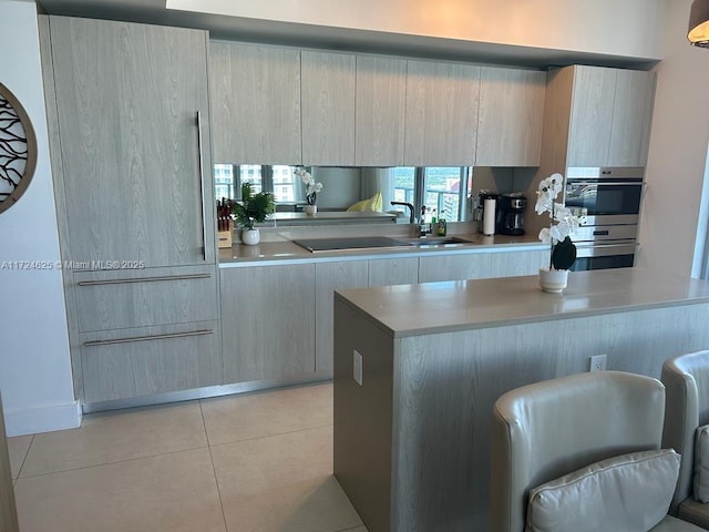 kitchen with light brown cabinetry, light tile patterned floors, and sink