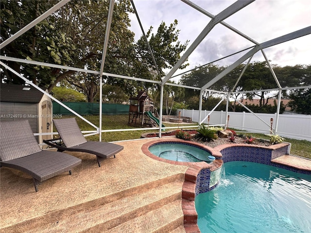 view of swimming pool with a storage shed, glass enclosure, a playground, and an in ground hot tub