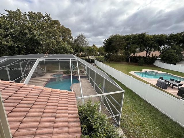 view of pool featuring an in ground hot tub, a yard, glass enclosure, and a patio