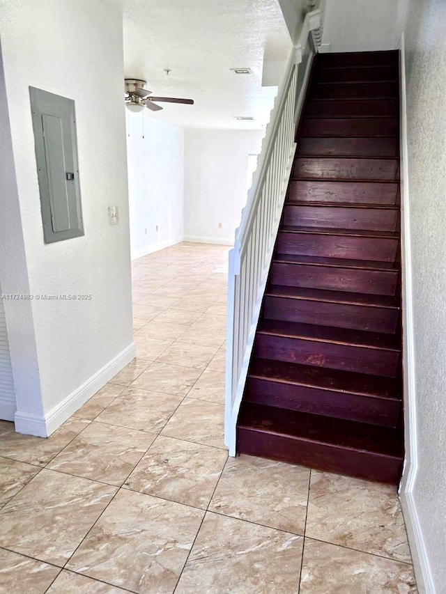 staircase with electric panel, ceiling fan, visible vents, and baseboards