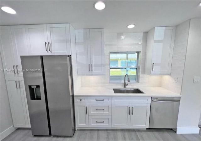 kitchen featuring backsplash, white cabinetry, sink, and appliances with stainless steel finishes