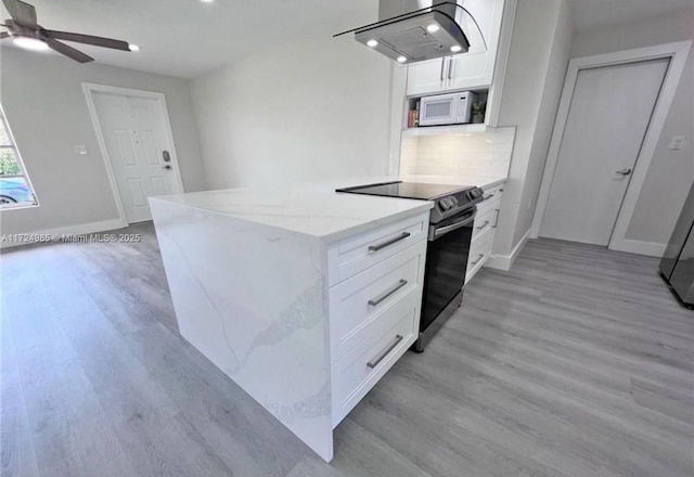 kitchen with light stone counters, electric stove, light hardwood / wood-style floors, white cabinetry, and range hood