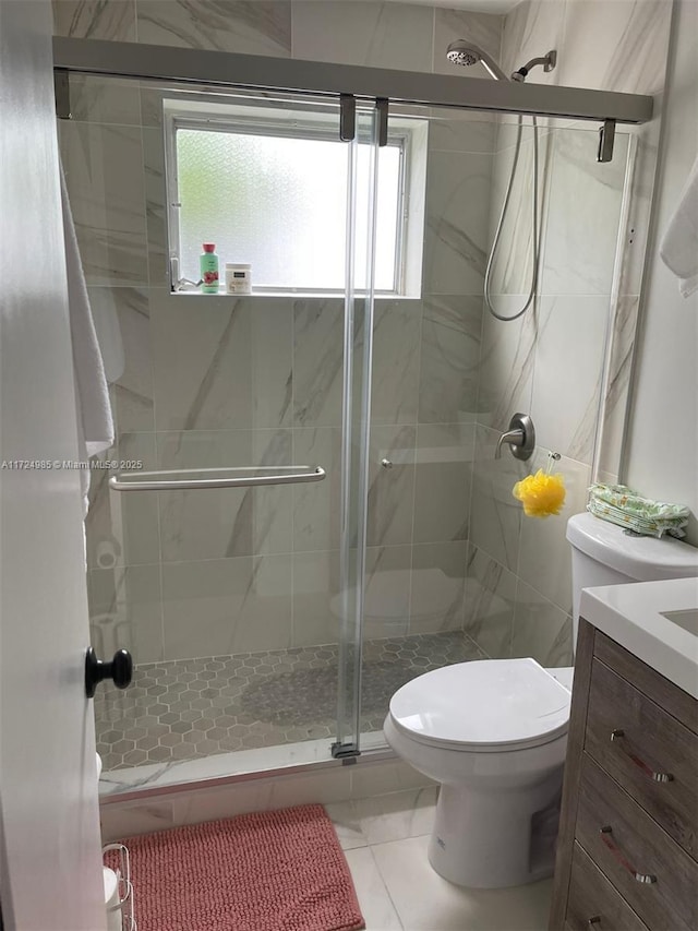 bathroom featuring toilet, vanity, tile patterned floors, and a shower with shower door