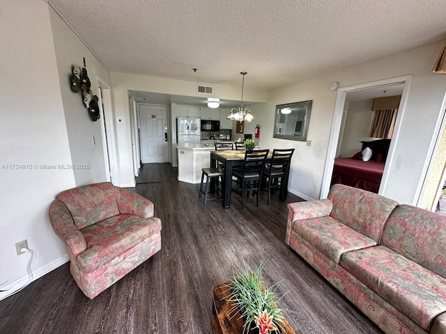 living room featuring dark hardwood / wood-style flooring, a textured ceiling, and a chandelier