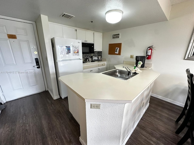 kitchen featuring backsplash, white refrigerator, sink, white cabinetry, and kitchen peninsula