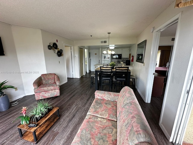 living room with dark hardwood / wood-style floors, a textured ceiling, and a notable chandelier