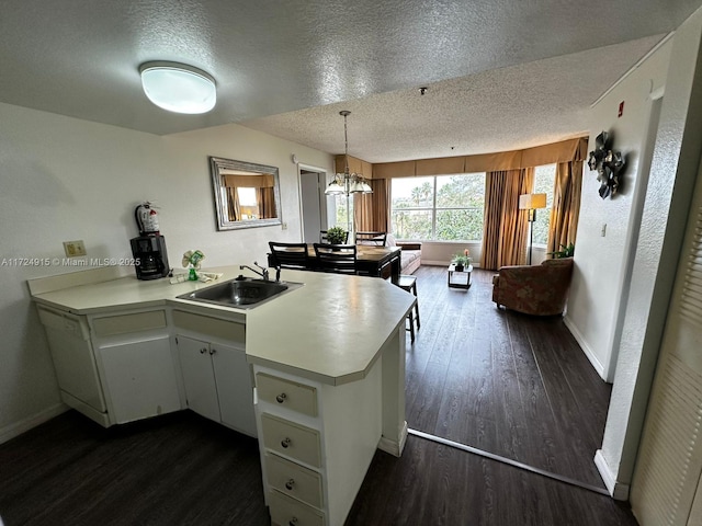 kitchen with dark wood-type flooring, white cabinets, sink, a textured ceiling, and kitchen peninsula