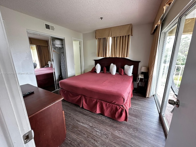 bedroom with dark hardwood / wood-style floors, access to exterior, a textured ceiling, and a closet