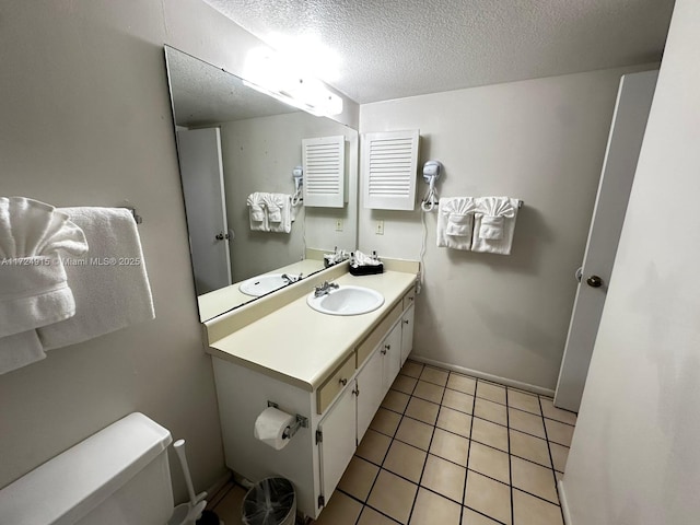 bathroom with tile patterned flooring, vanity, a textured ceiling, and toilet