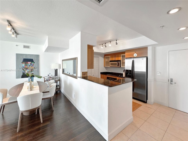 kitchen featuring a textured ceiling, stainless steel appliances, rail lighting, and kitchen peninsula