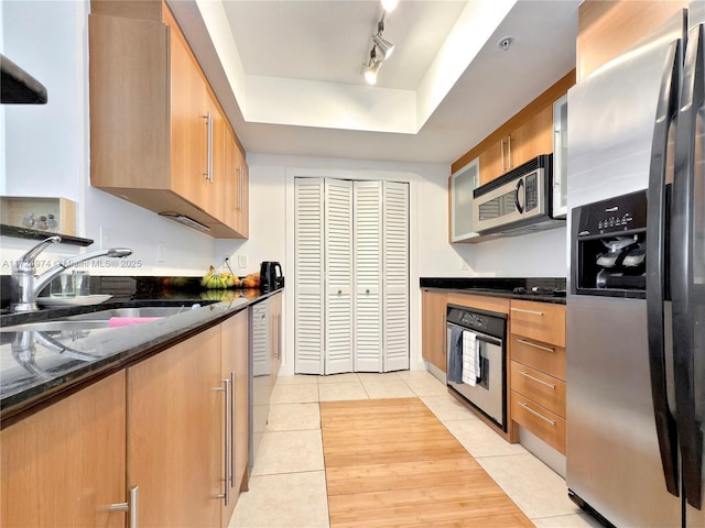 kitchen with sink, light tile patterned flooring, a tray ceiling, and stainless steel appliances