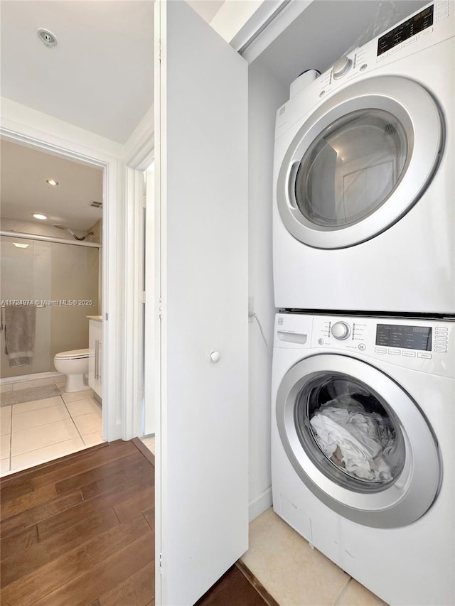 clothes washing area featuring tile patterned floors and stacked washer and clothes dryer