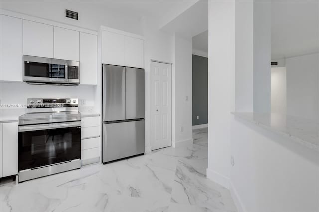 kitchen featuring stainless steel appliances, white cabinetry, and light stone counters