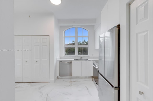 kitchen featuring marble finish floor, light countertops, appliances with stainless steel finishes, white cabinetry, and a sink