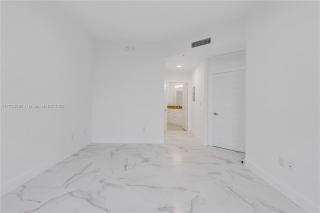 empty room with marble finish floor, baseboards, and visible vents