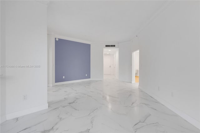 spare room with crown molding, marble finish floor, and baseboards