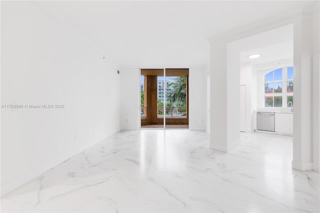 empty room featuring marble finish floor, a healthy amount of sunlight, and baseboards