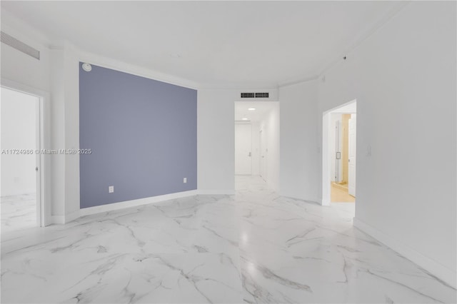 spare room with marble finish floor, ornamental molding, visible vents, and baseboards