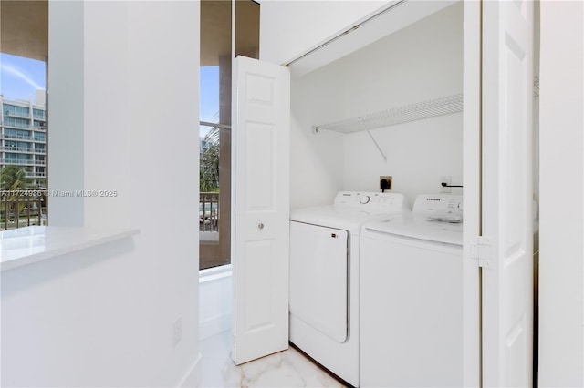 clothes washing area featuring a healthy amount of sunlight, laundry area, marble finish floor, and washer and dryer