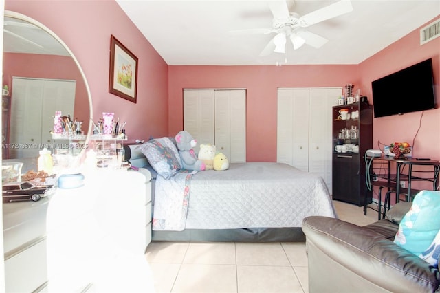 tiled bedroom featuring multiple closets and ceiling fan