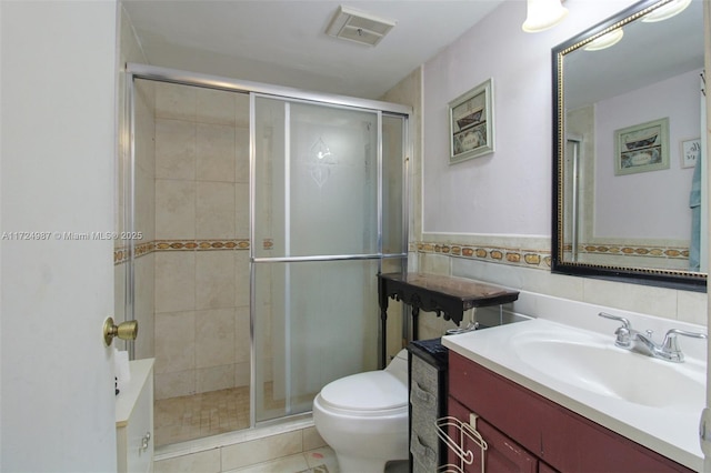 bathroom featuring vanity, tile walls, tile patterned flooring, toilet, and a shower with shower door