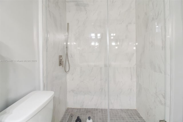 bathroom featuring a shower with shower door and toilet