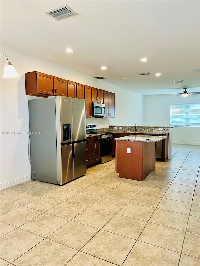 kitchen with ceiling fan, hanging light fixtures, stainless steel appliances, light tile patterned floors, and a kitchen island