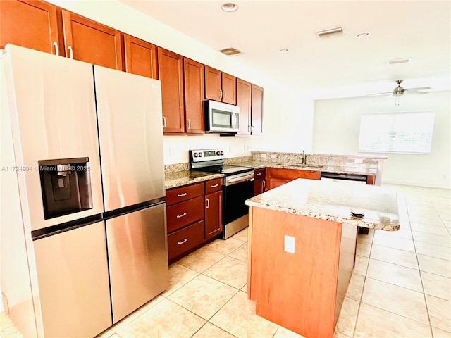 kitchen featuring sink, light stone countertops, a kitchen island, kitchen peninsula, and stainless steel appliances