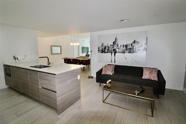 kitchen with light hardwood / wood-style flooring, an inviting chandelier, hanging light fixtures, and sink