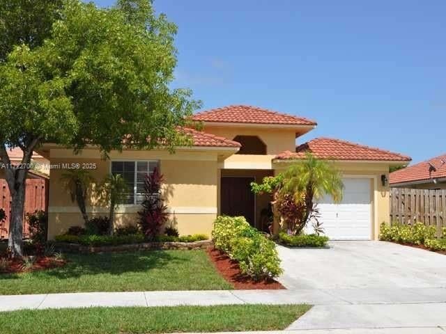 mediterranean / spanish house featuring a garage and a front yard