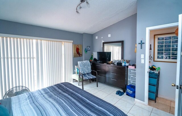 bedroom with light tile patterned floors, vaulted ceiling, and a textured ceiling