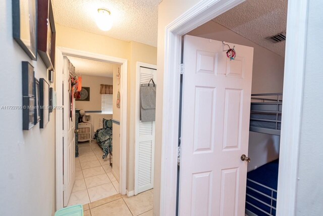 hallway featuring a textured ceiling and light tile patterned flooring