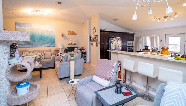 living room featuring light tile patterned floors, sink, a textured ceiling, and lofted ceiling