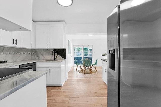 kitchen featuring stainless steel refrigerator with ice dispenser, sink, white cabinetry, light stone countertops, and light hardwood / wood-style floors