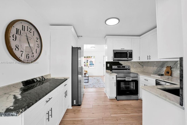 kitchen with white cabinetry, appliances with stainless steel finishes, and dark stone countertops