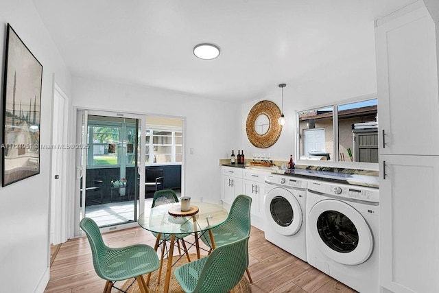 washroom with cabinets, separate washer and dryer, and light hardwood / wood-style flooring