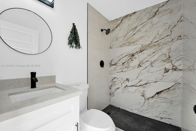 bathroom with tiled shower, vanity, and toilet