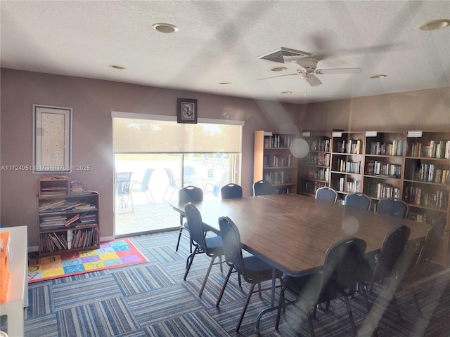 dining space with ceiling fan, carpet flooring, and a textured ceiling