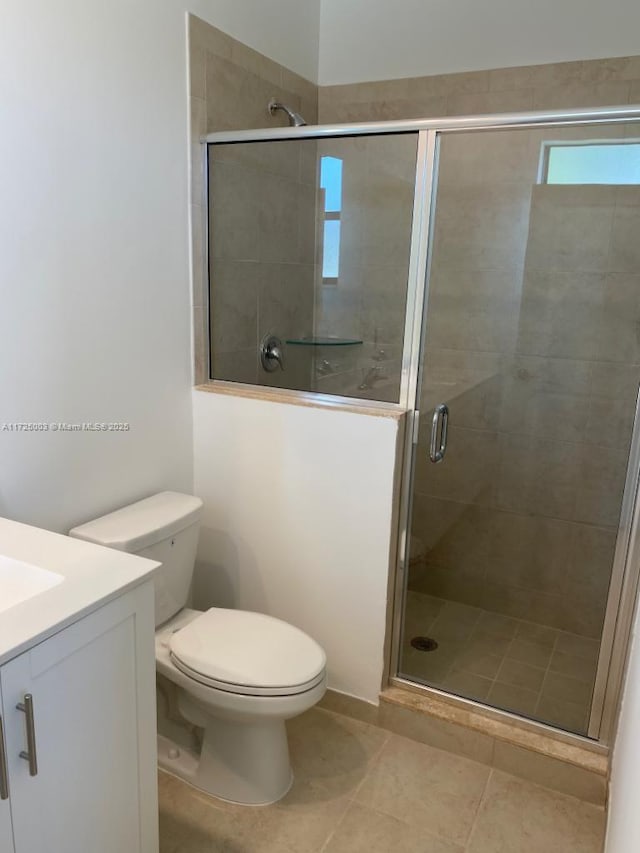 bathroom featuring tile patterned flooring, vanity, toilet, and walk in shower