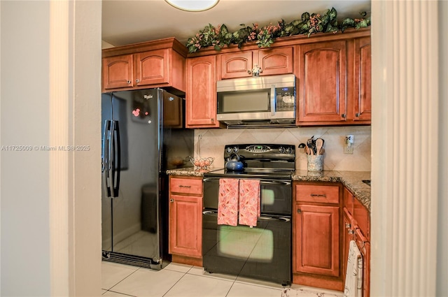 kitchen with light tile patterned flooring, backsplash, dark stone counters, and black appliances