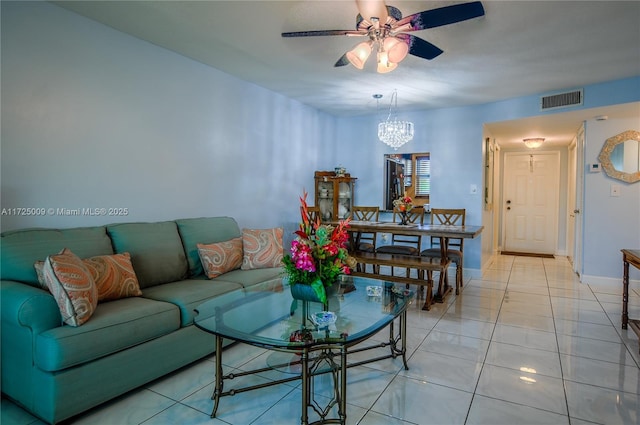 tiled living room with ceiling fan with notable chandelier