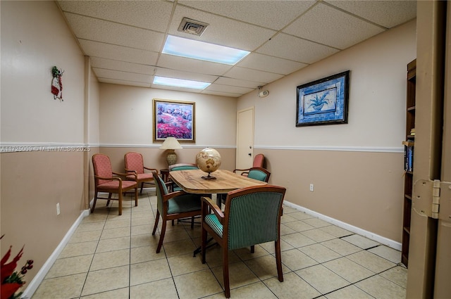 dining area featuring light tile patterned floors and a paneled ceiling