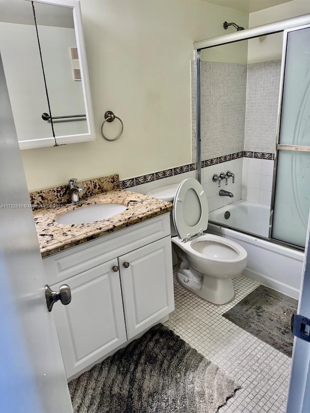 full bathroom featuring shower / bath combination with glass door, vanity, tile patterned floors, and toilet