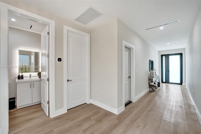 hallway with sink and light hardwood / wood-style floors