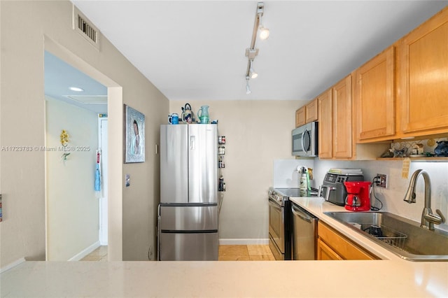 kitchen featuring track lighting, sink, decorative backsplash, light tile patterned floors, and stainless steel appliances